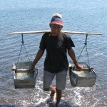 local man carrying sea water to make salt in Amed, Bali
