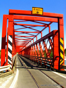 photos of New Zealand oddities include this one lane road and train bridge